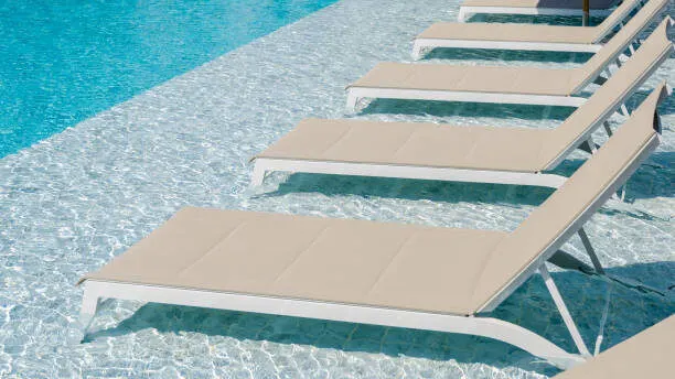 swimming pool with tanning ledge and lounge chairs in water.jpeg e1685432540200